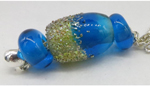 This focal bead was created with one half of the bead with CiM Limelight with DH fine Aurae glass frit.  Limelight is a great base for silver glass. The other half of the focal along with the two spacer beads are CiM Blue-yah.